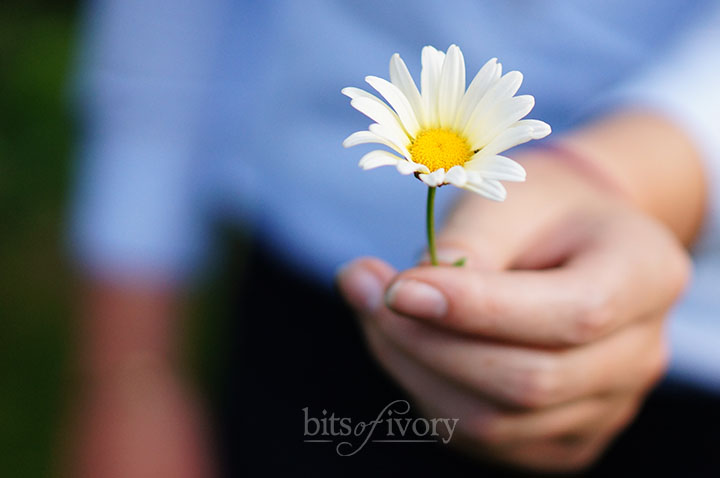 Woman giving a daisy - reasons you need to love yourself